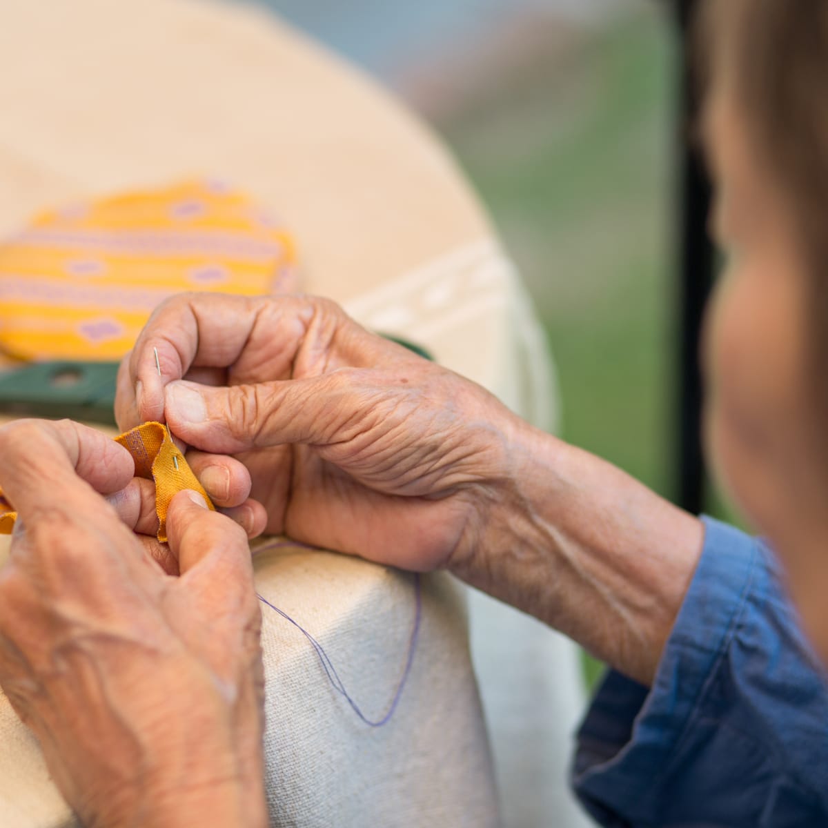 Close up of a womans hands sewing a piece of fabric