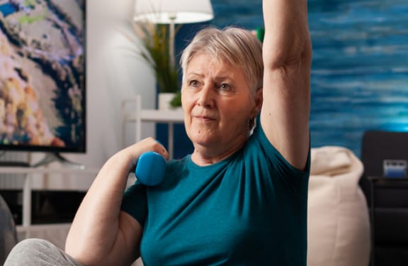 Elderly woman doing arm excercises with small weights