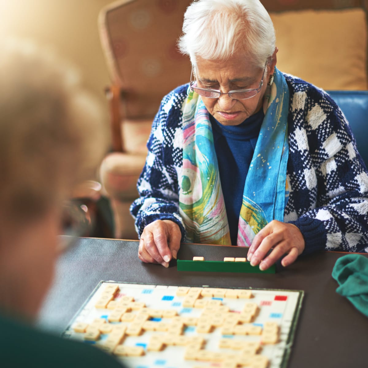 Older woman sitting at a table playing scrabble