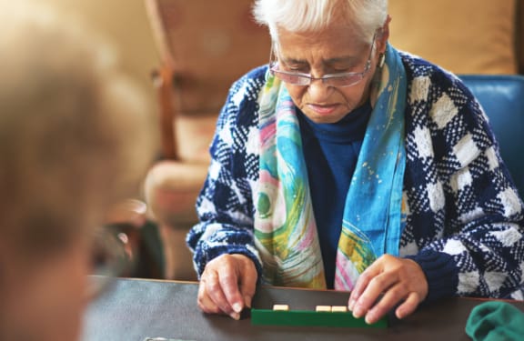 Older woman sitting at a table playing scrabble