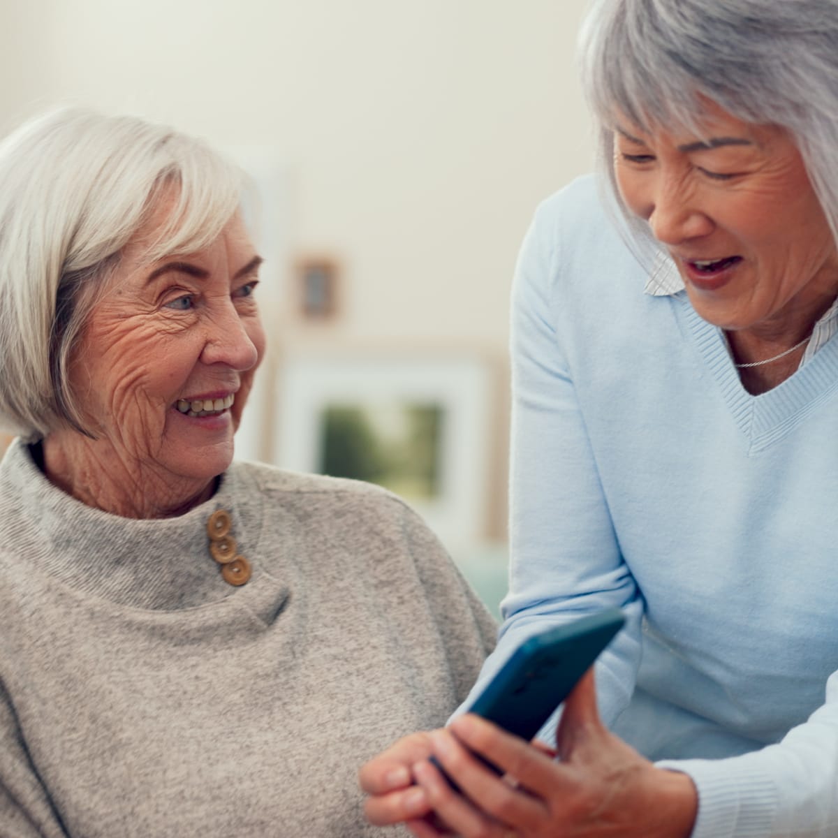 Two older woman looking at a phone and laughing