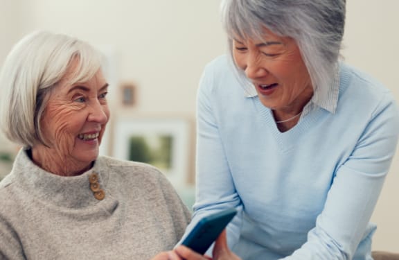 Two older woman looking at a phone and laughing