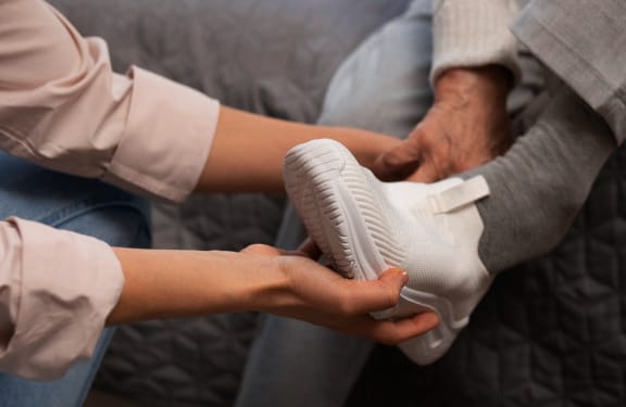 Woman putting a slip on show on an elderly mans foot